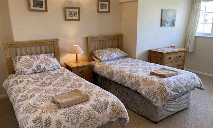 Spacious second bedroom with twin single beds and views of rear garden and the sea beyond